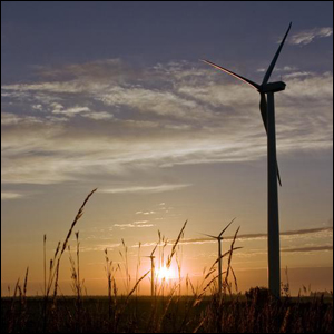 A photo of a sunset, large wind turbines, and wheat. 