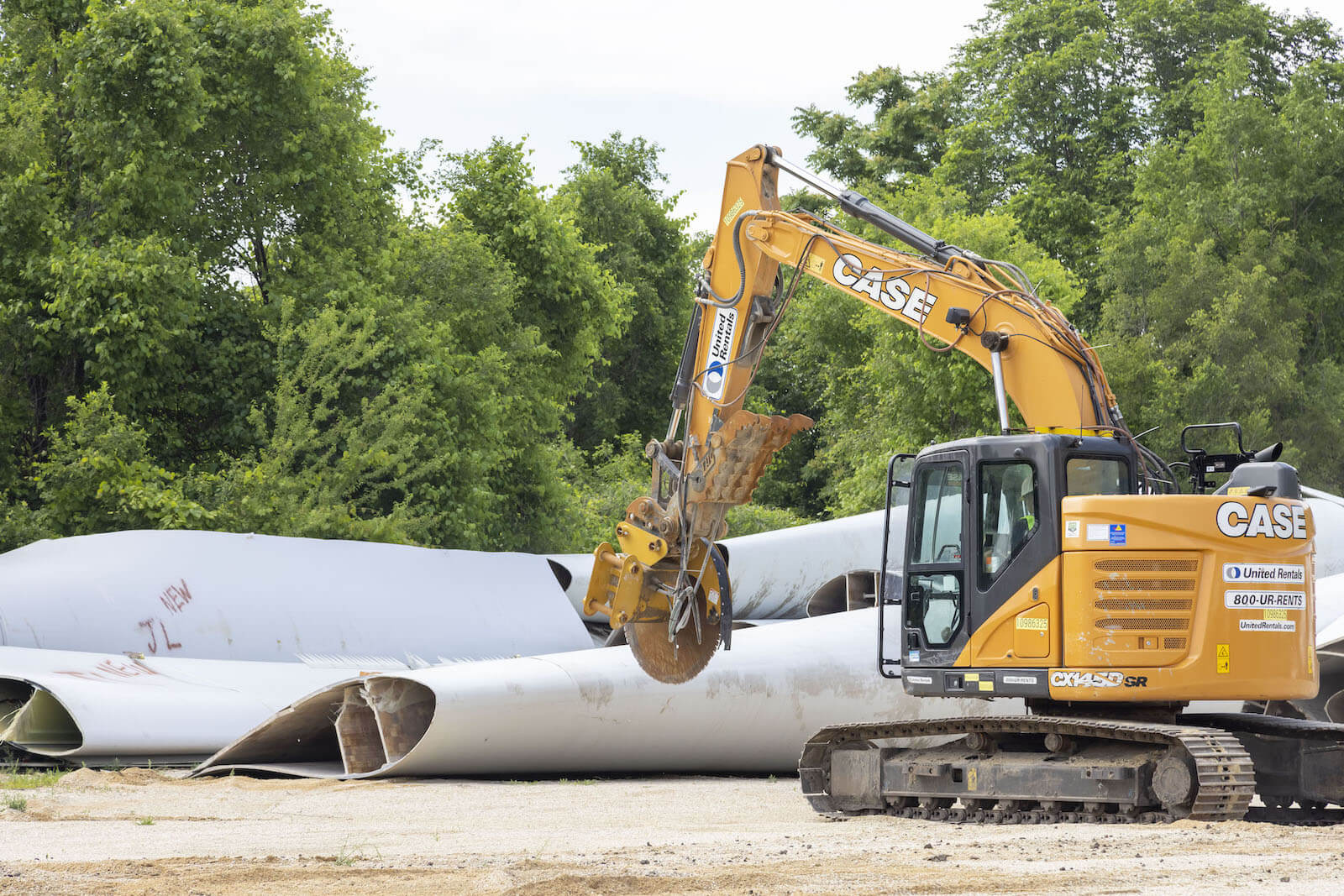 A bulldozer moves past wind turbine blades on the ground.