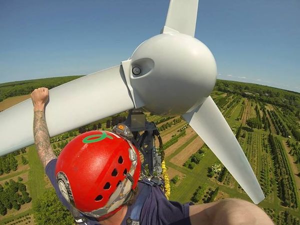 photo of a person performing maintenance at the top of a wind turbine