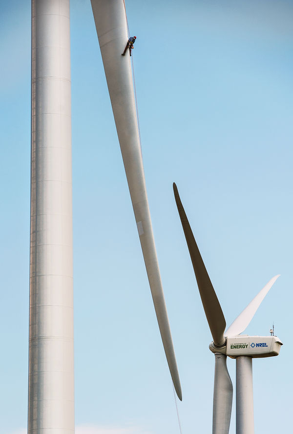 photo of a person repelling from a large wind turbine blade