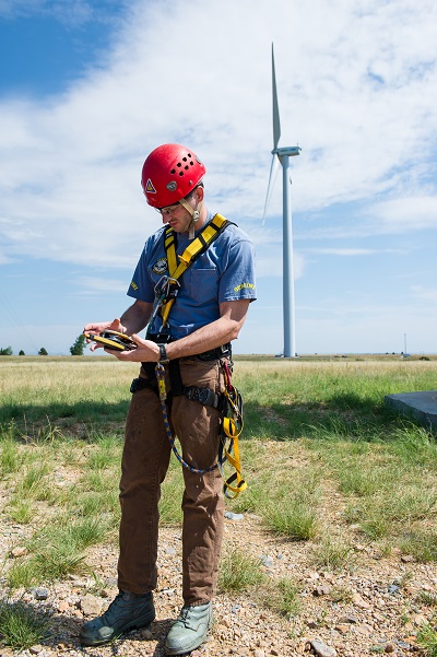 photo of a man taking measurements near a wind turbine