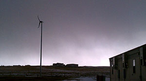 Photo of a wind turbine in front of an elementary school on a cloudy day.